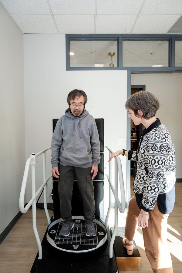 A patient on a balance platform with a therapist beside him